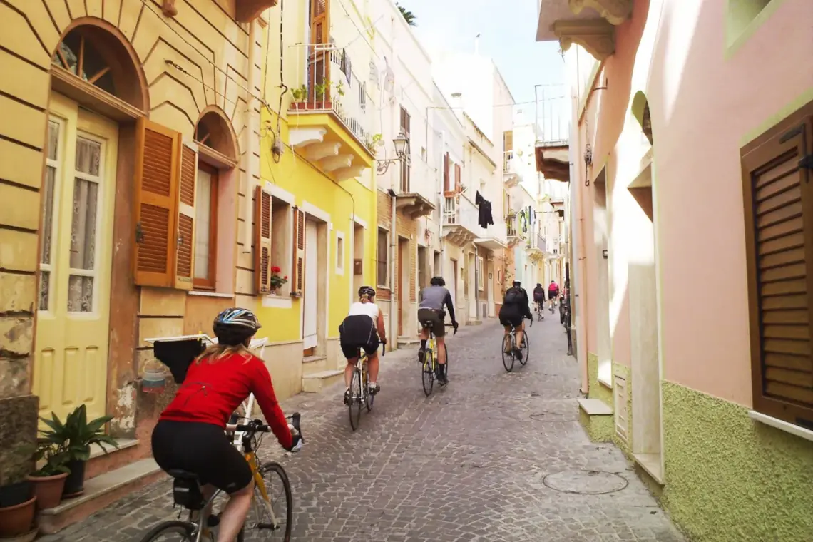 Cycle tourists riding through a narrow street in Sardinia